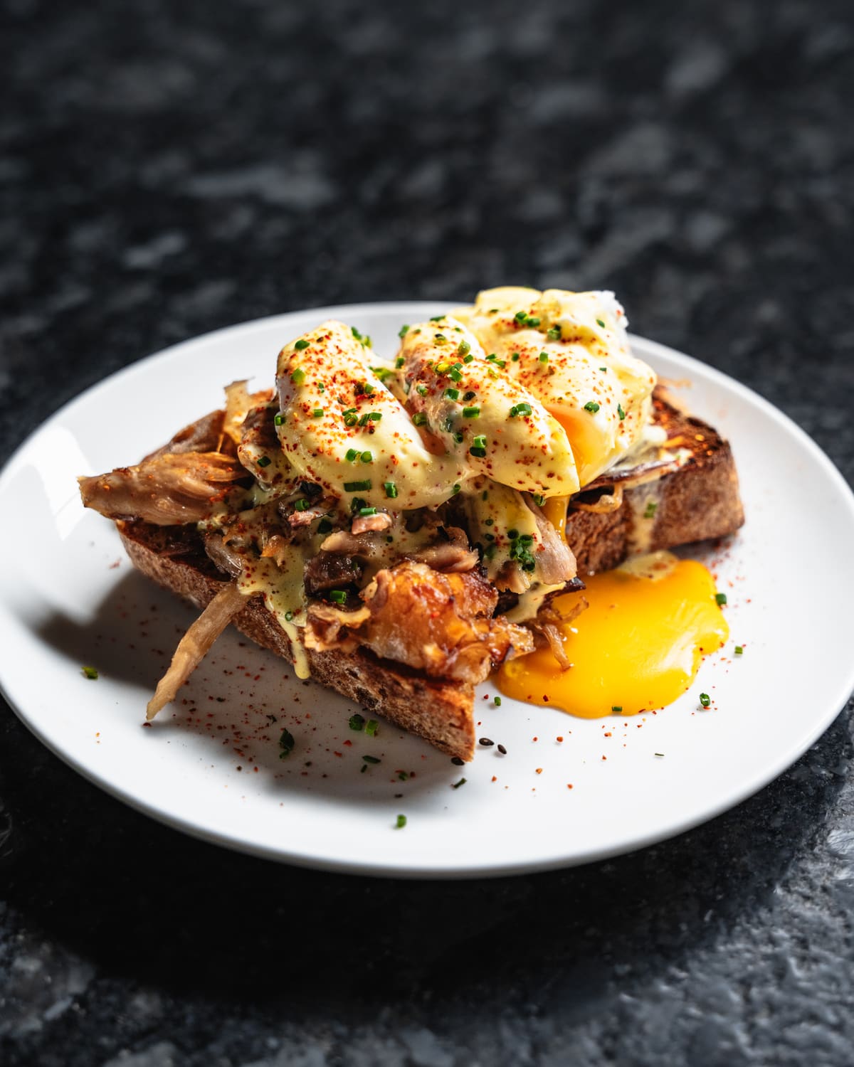 Hog Shoulder Benny on a white plate: pulled pork, poached eggs and hollandaise on toast